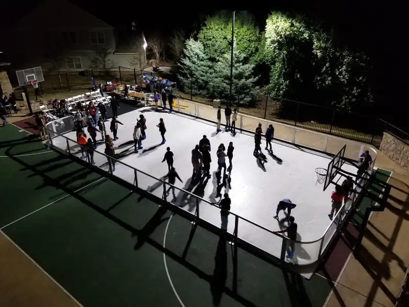 A large illuminated Amanzi synthetic ice rink filled with guests at an evening event