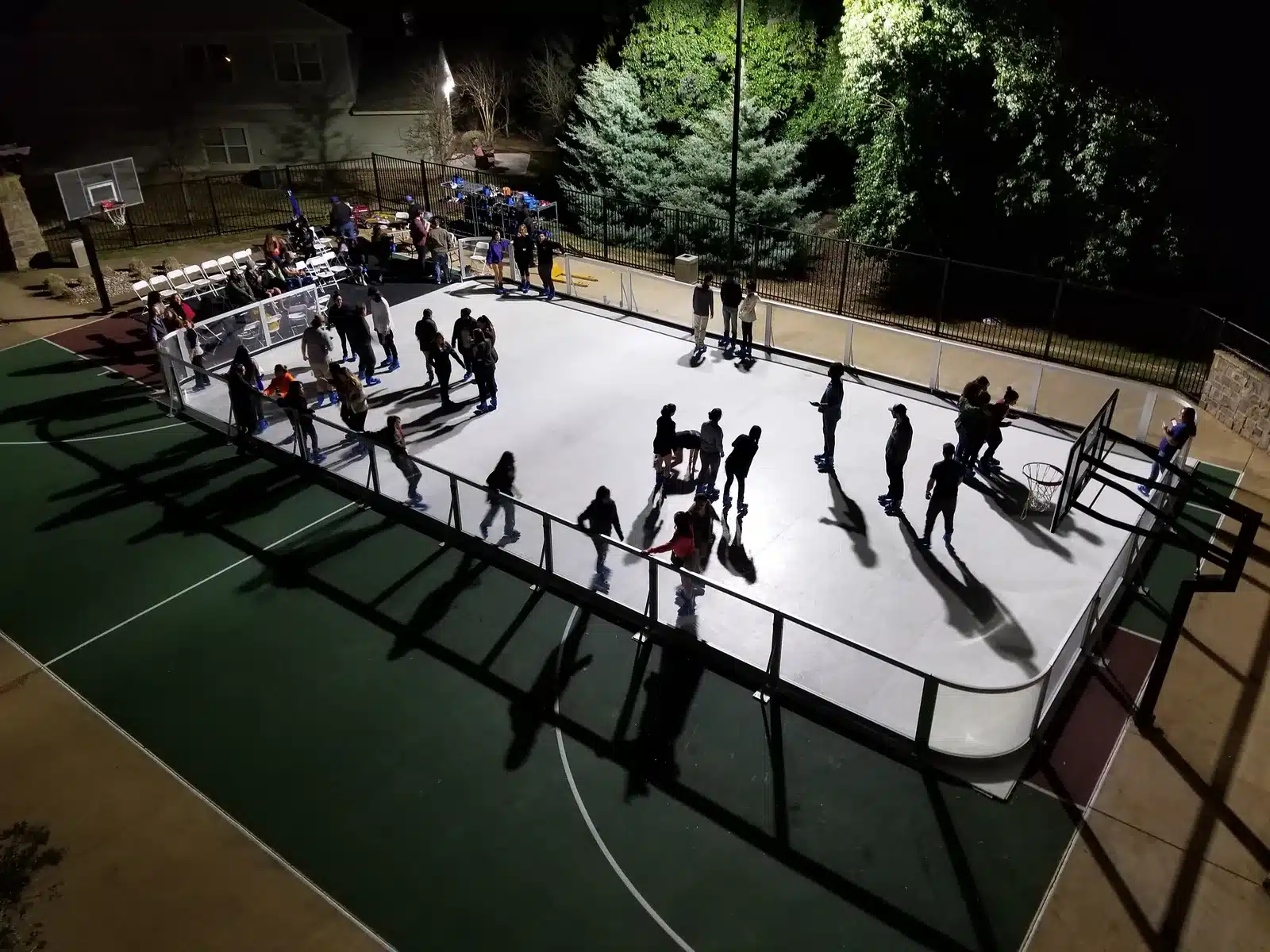A busy illuminated Amanzi synthetic ice rink filled with guests at a nighttime event